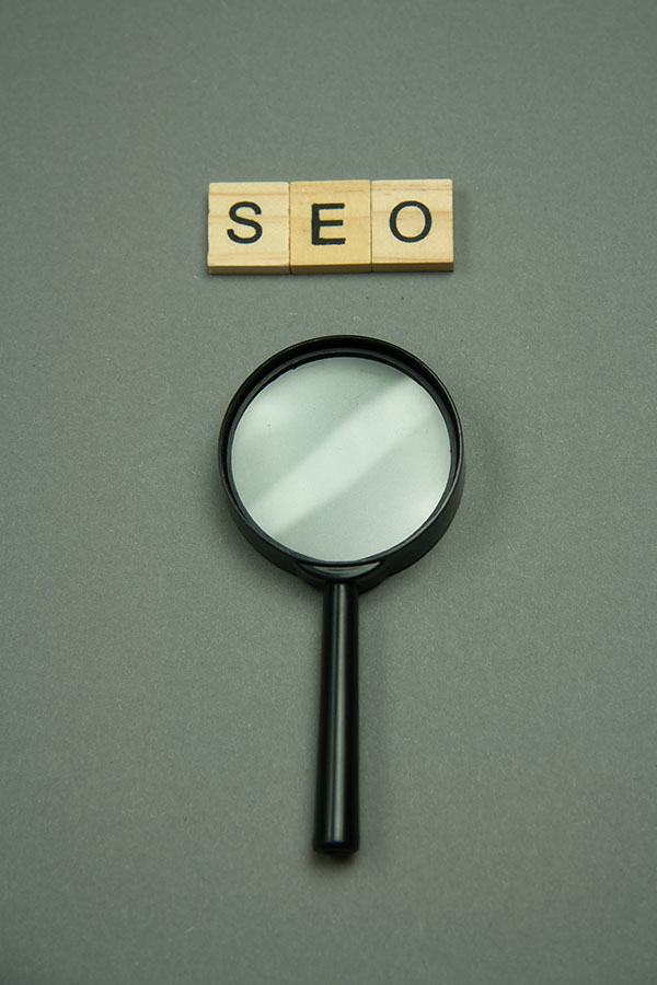 SEO written in wooden letters and magnifying glass.